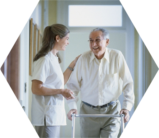 A nurse and an elderly man in a hallway.